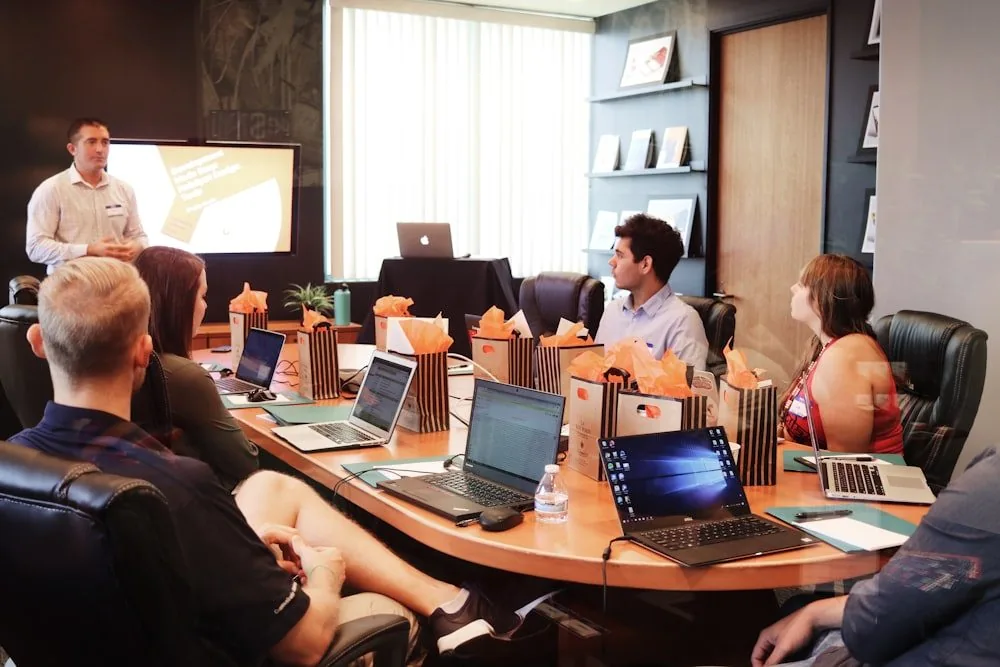 A leadership team around a boardroom table during a presentation