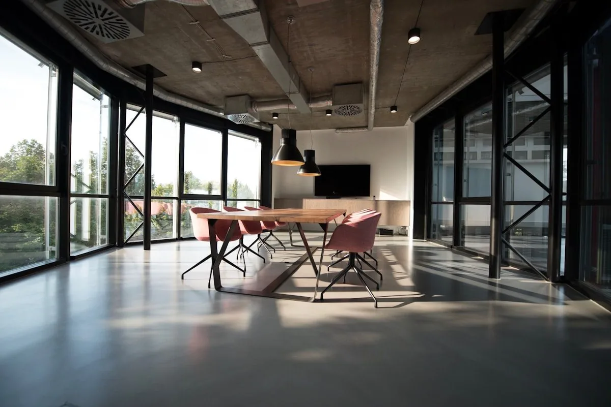 A modern glass-walled meeting room with a long wooden table