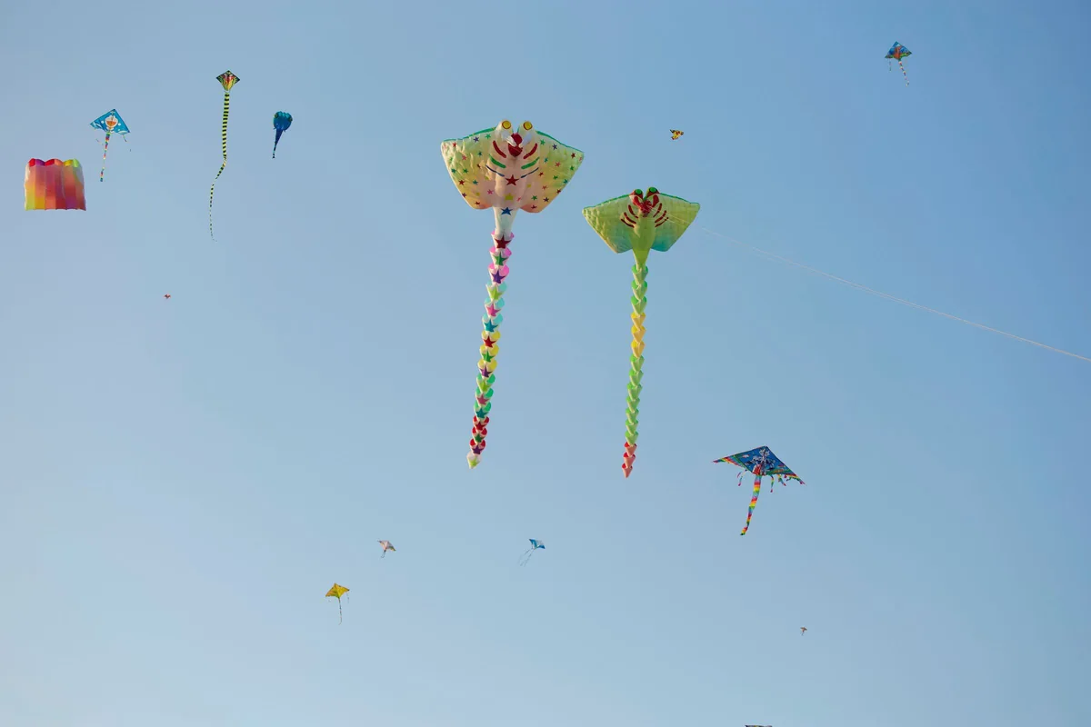Colourful kites flying high against a clear blue sky