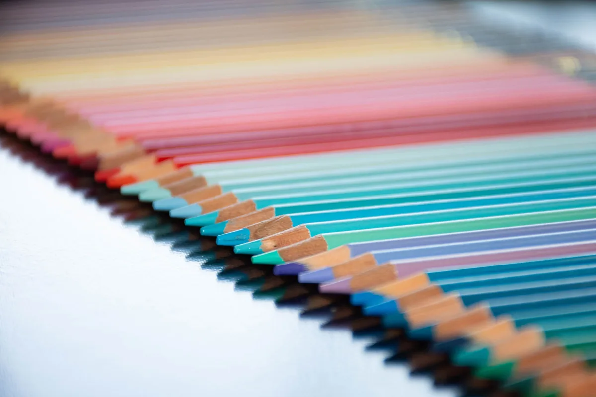 A spectrum of sharpened coloured pencils lined up in order