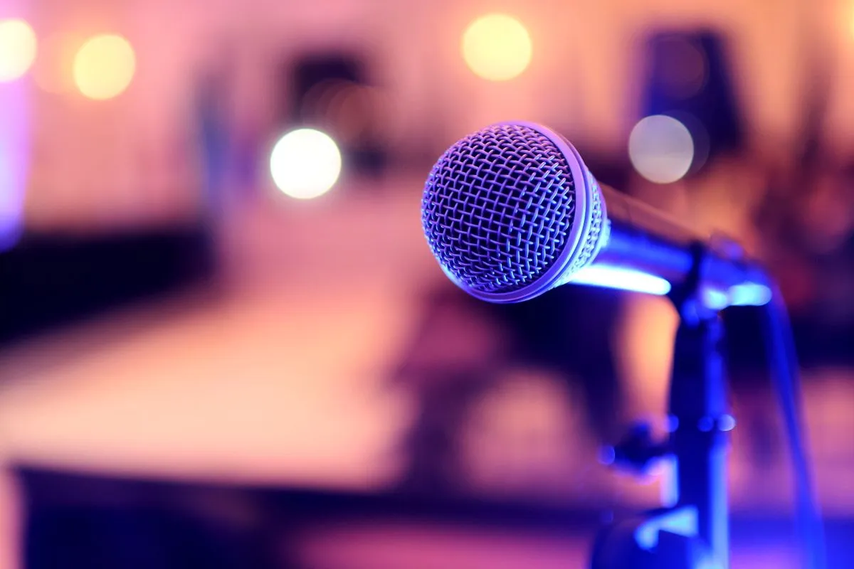 A microphone on a stand lit in pink and violet light