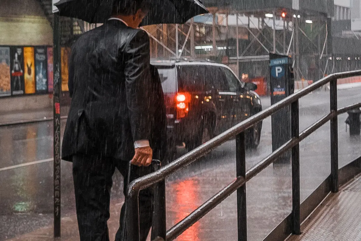A businessman with an umbrella on a rainy city street