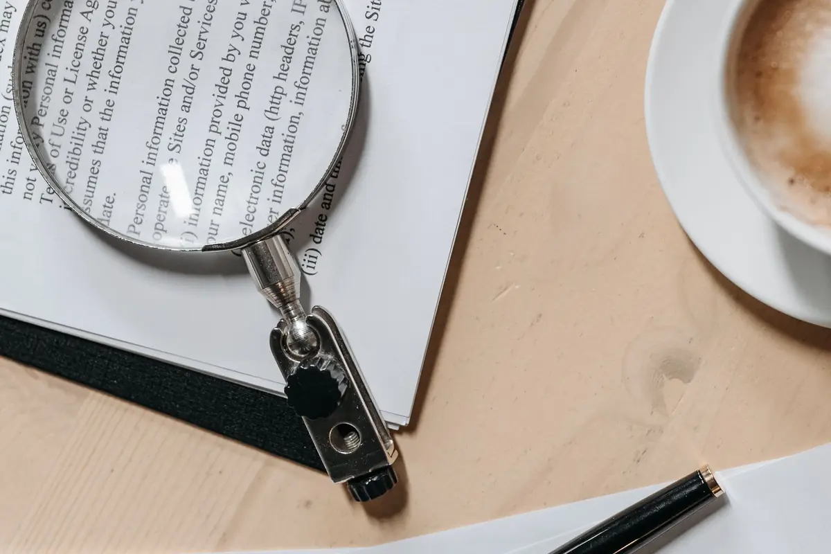 Documents under a magnifying glass with a pen