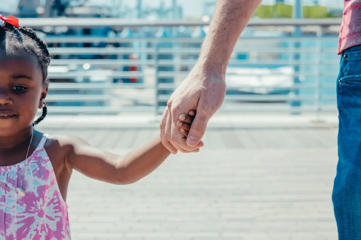 A father holding hands with his young daughter outdoors