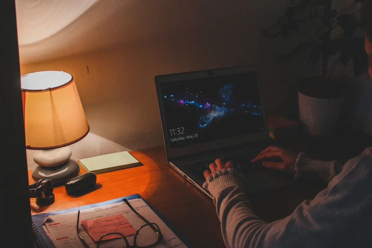 A lamplit desk with a laptop working into the night