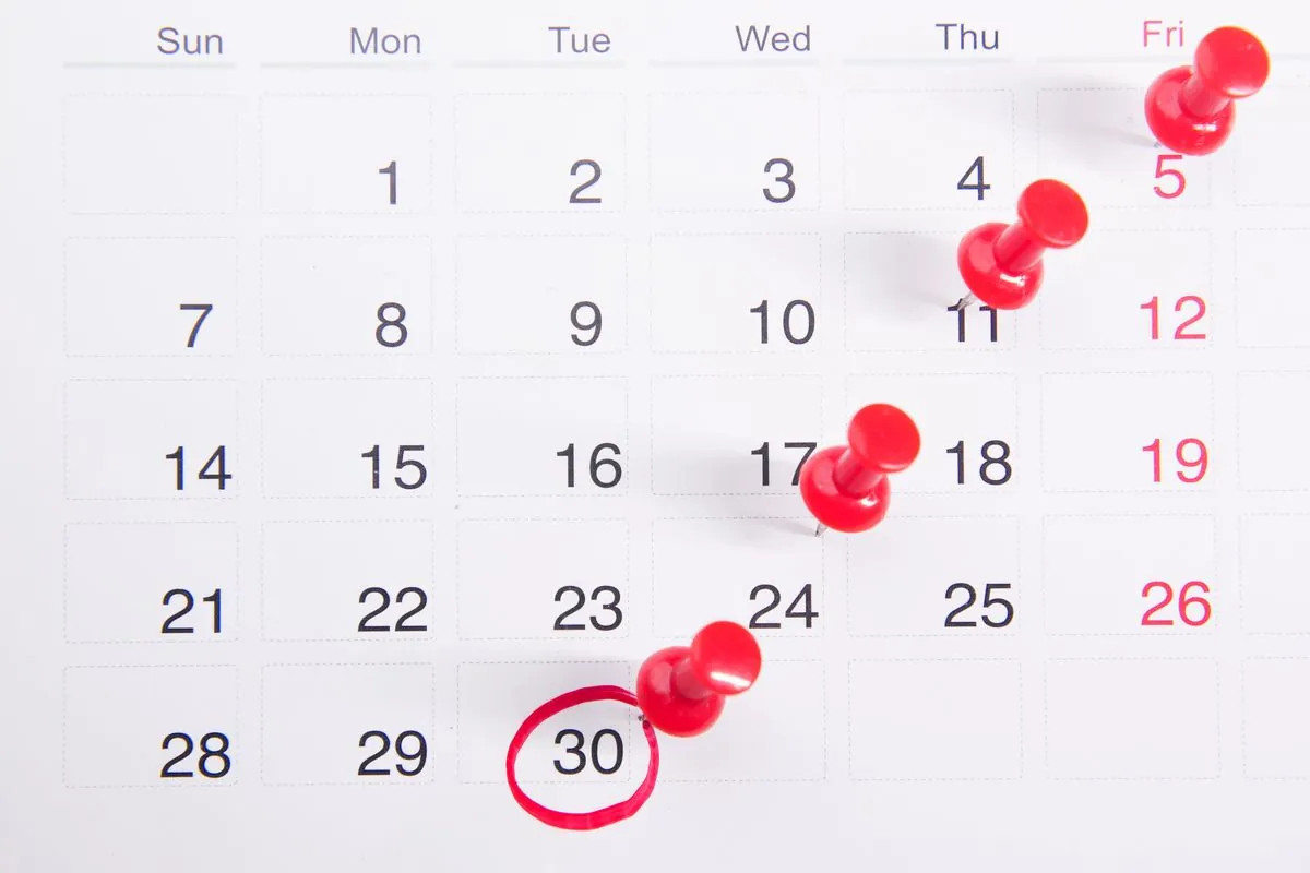 A wall calendar with a date circled in red and pins marking days