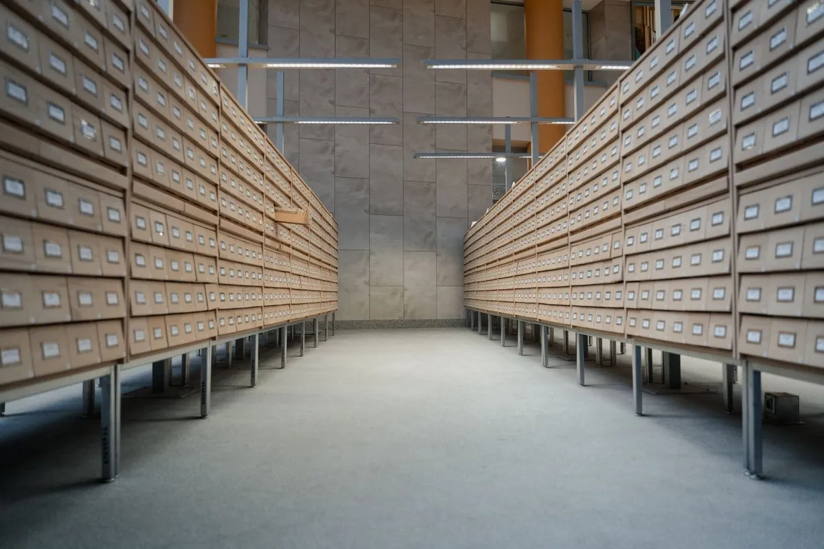 Rows of archive boxes on shelving receding down an aisle
