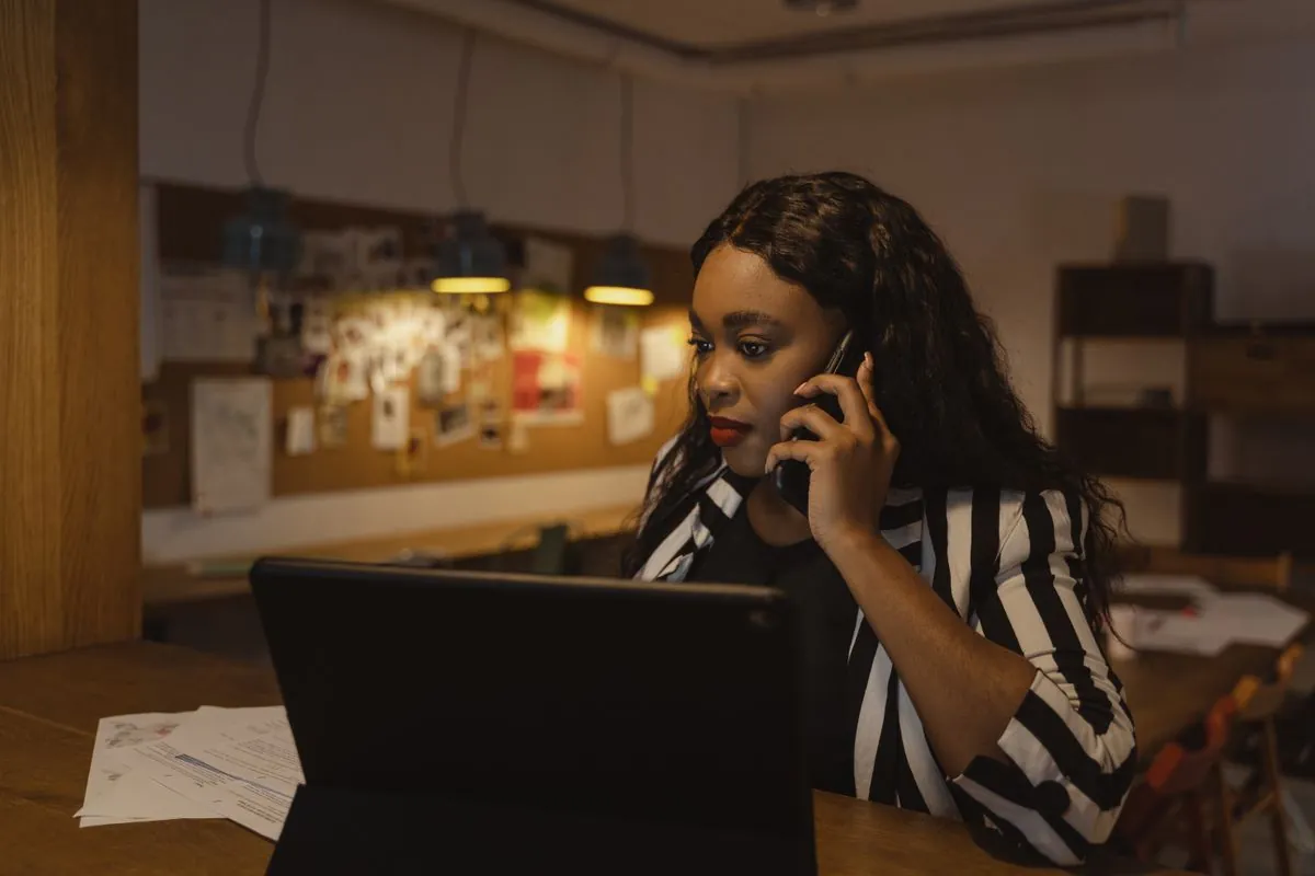 A professional taking a call at a desk beside a tablet
