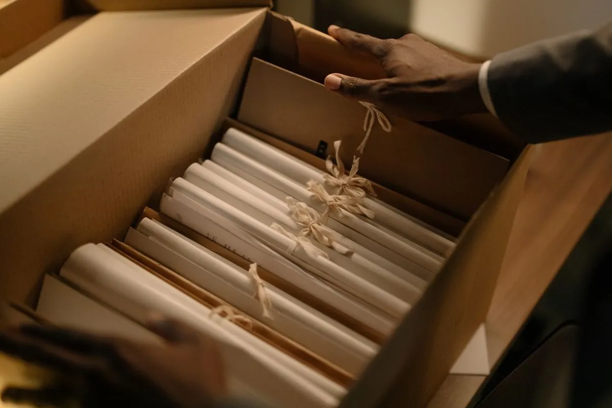Hands lifting tied bundles of papers from an archive box