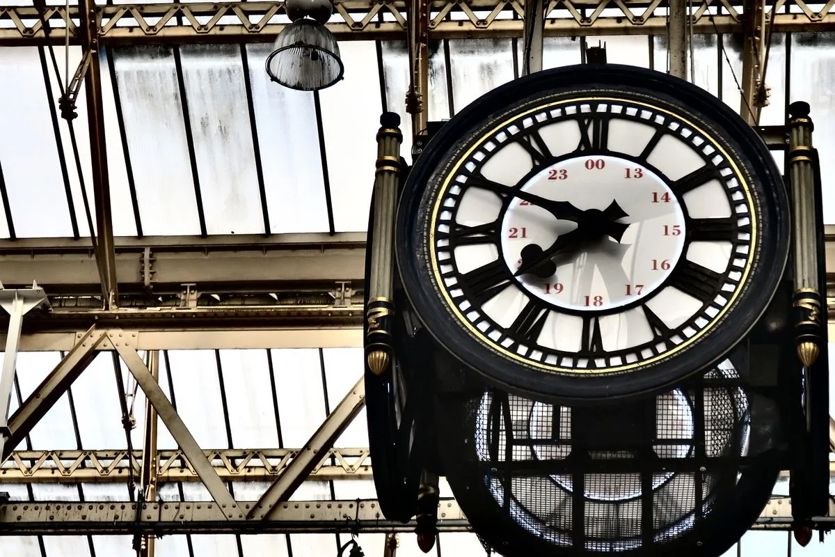A four-faced clock hanging beneath a glazed station roof