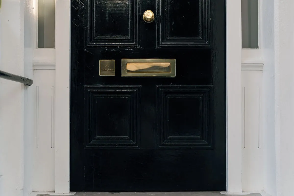 A black panelled front door with a brass letter plate