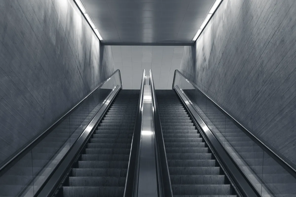 Twin escalators rising side by side in a concrete underpass