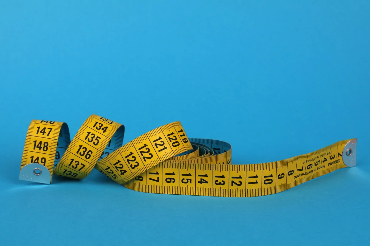 A yellow tape measure uncoiled on a bright blue background