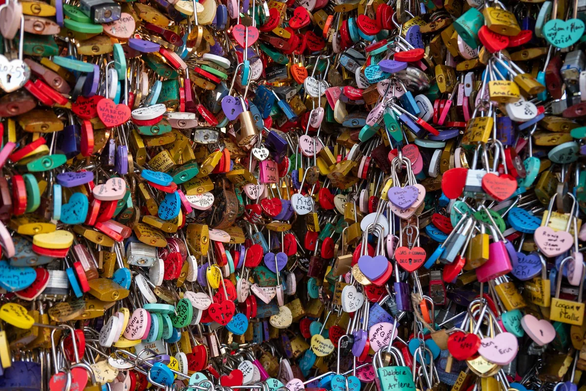 Rows of brightly coloured padlocks fastened to a railing